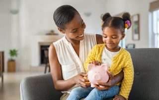 Mother and child putting coins into a piggy bank together