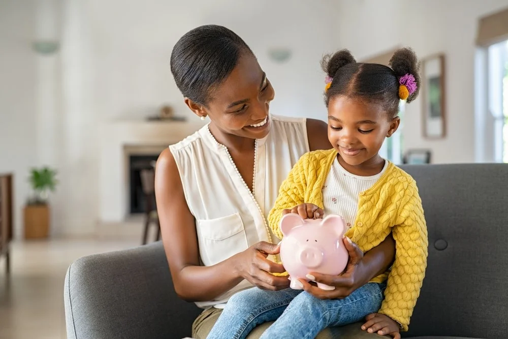 Mother and child putting coins into a piggy bank together