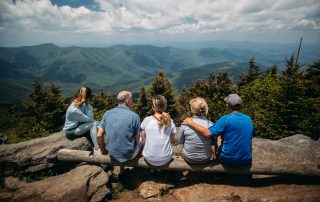 Intergenerational Wealth - Family sitting on a log overlooking forest
